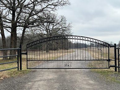 Completed custom arched steel driveway gate in North Texas