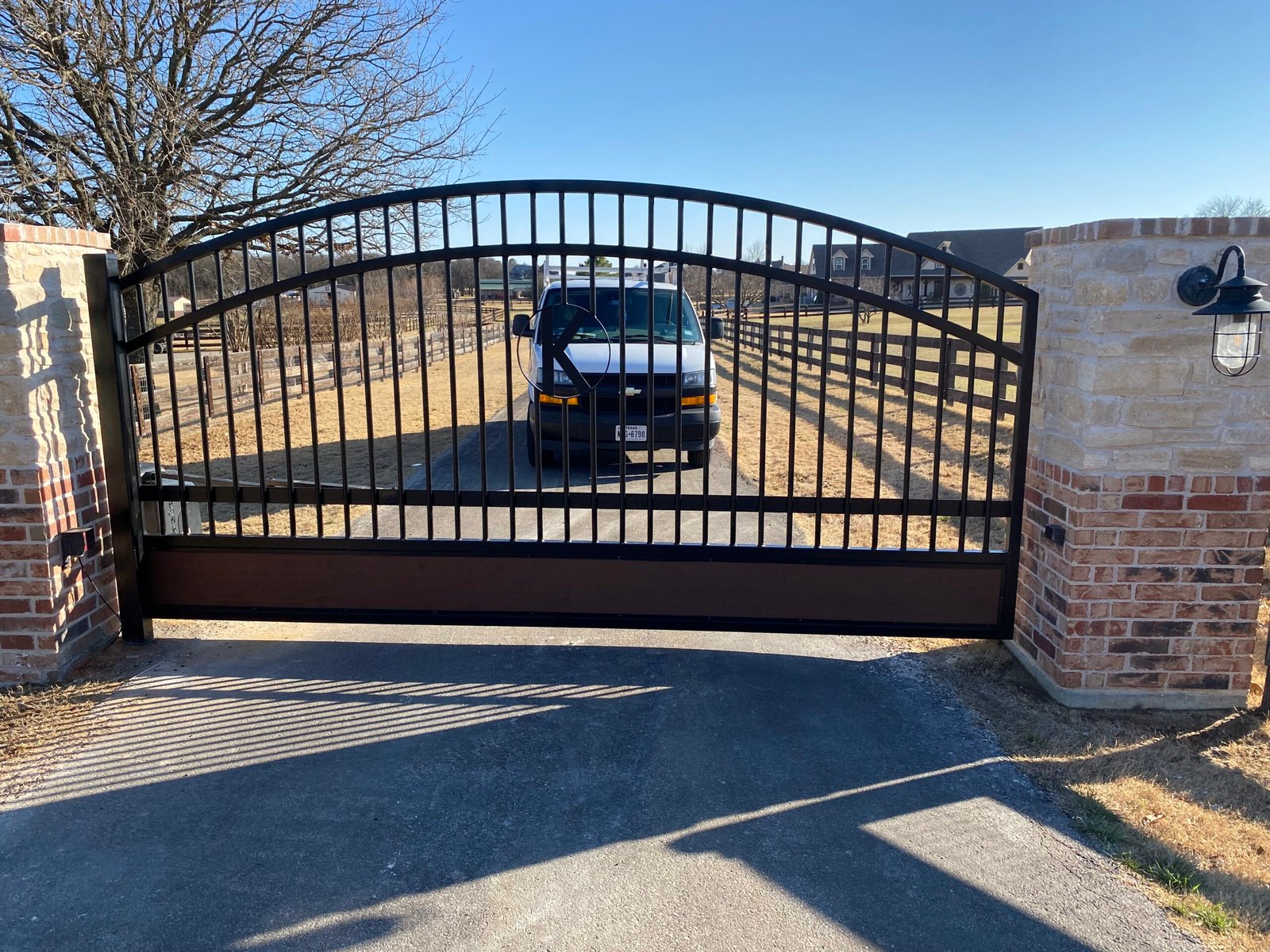 Original custom driveway gate with wood accent panels in North Texas