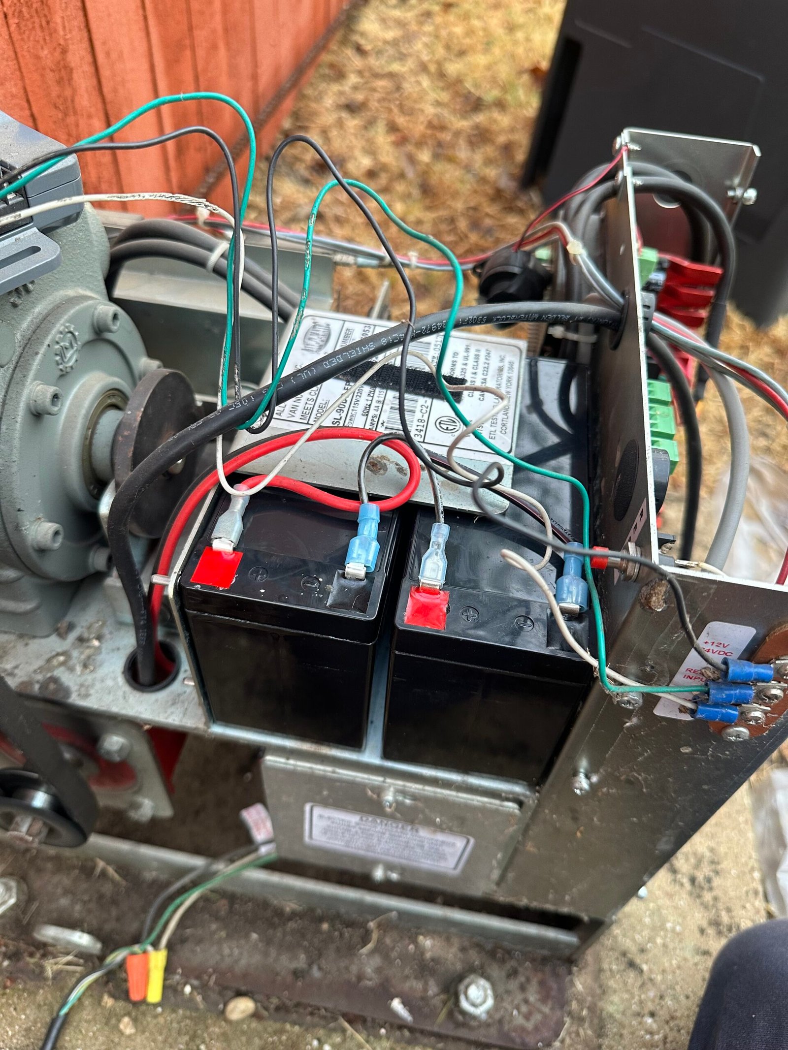 Two replacement batteries installed inside an All-O-Matic sliding-gate operator