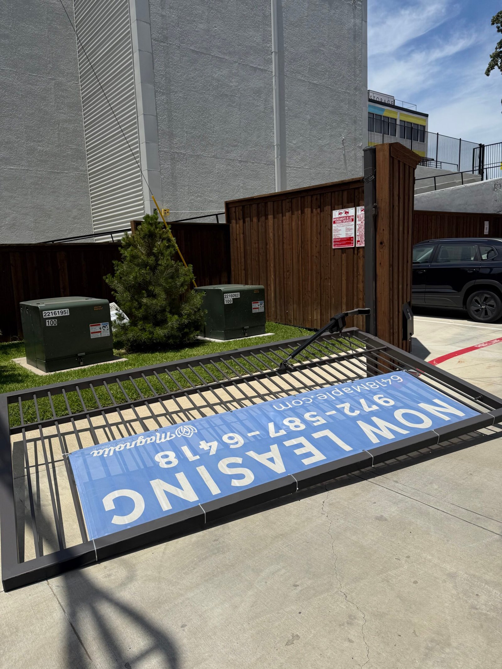 Commercial swing-gate leaf resting on the driveway before hinge replacement in Dallas