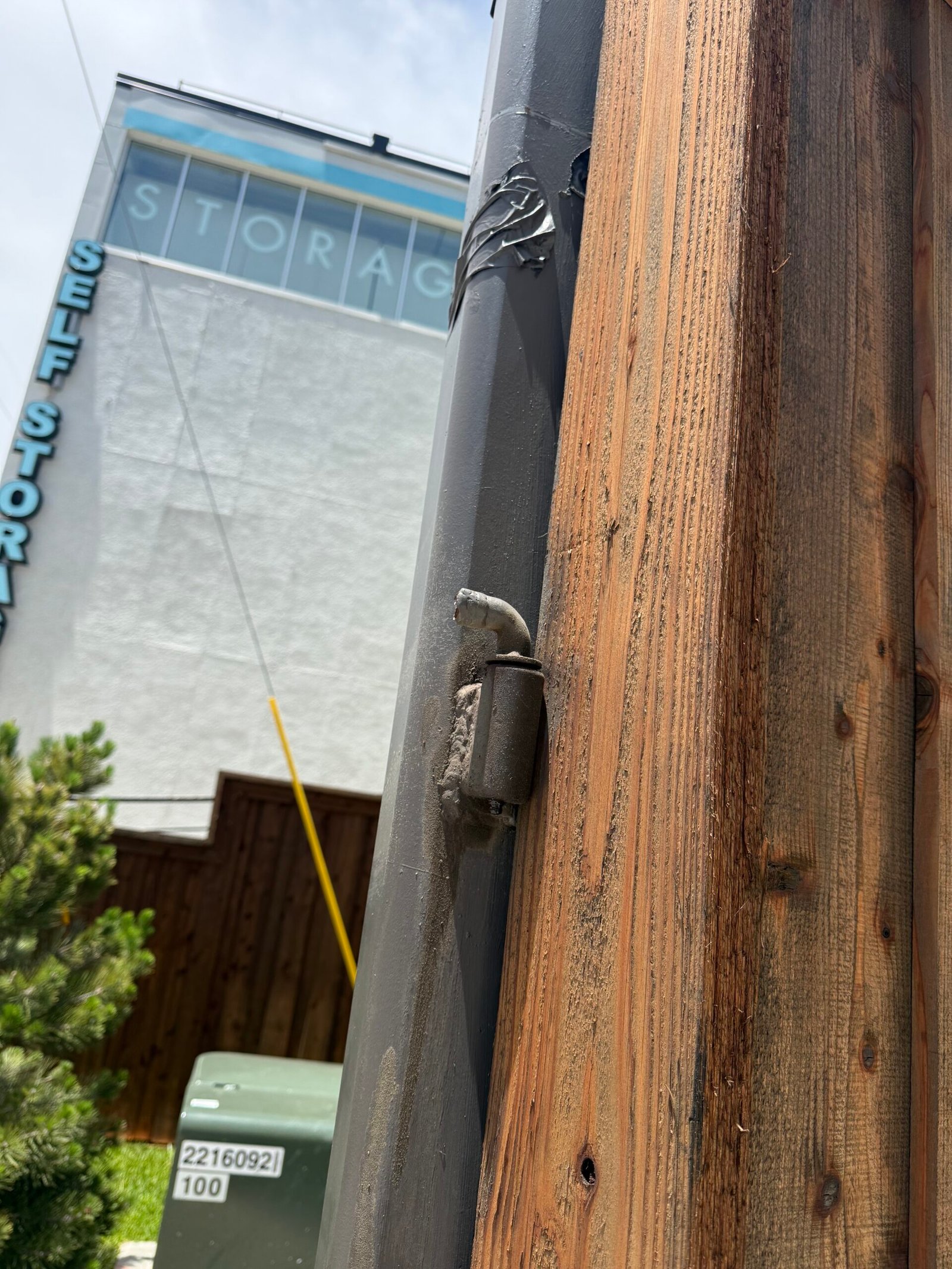 Close view of the commercial swing-gate hinge area before replacement
