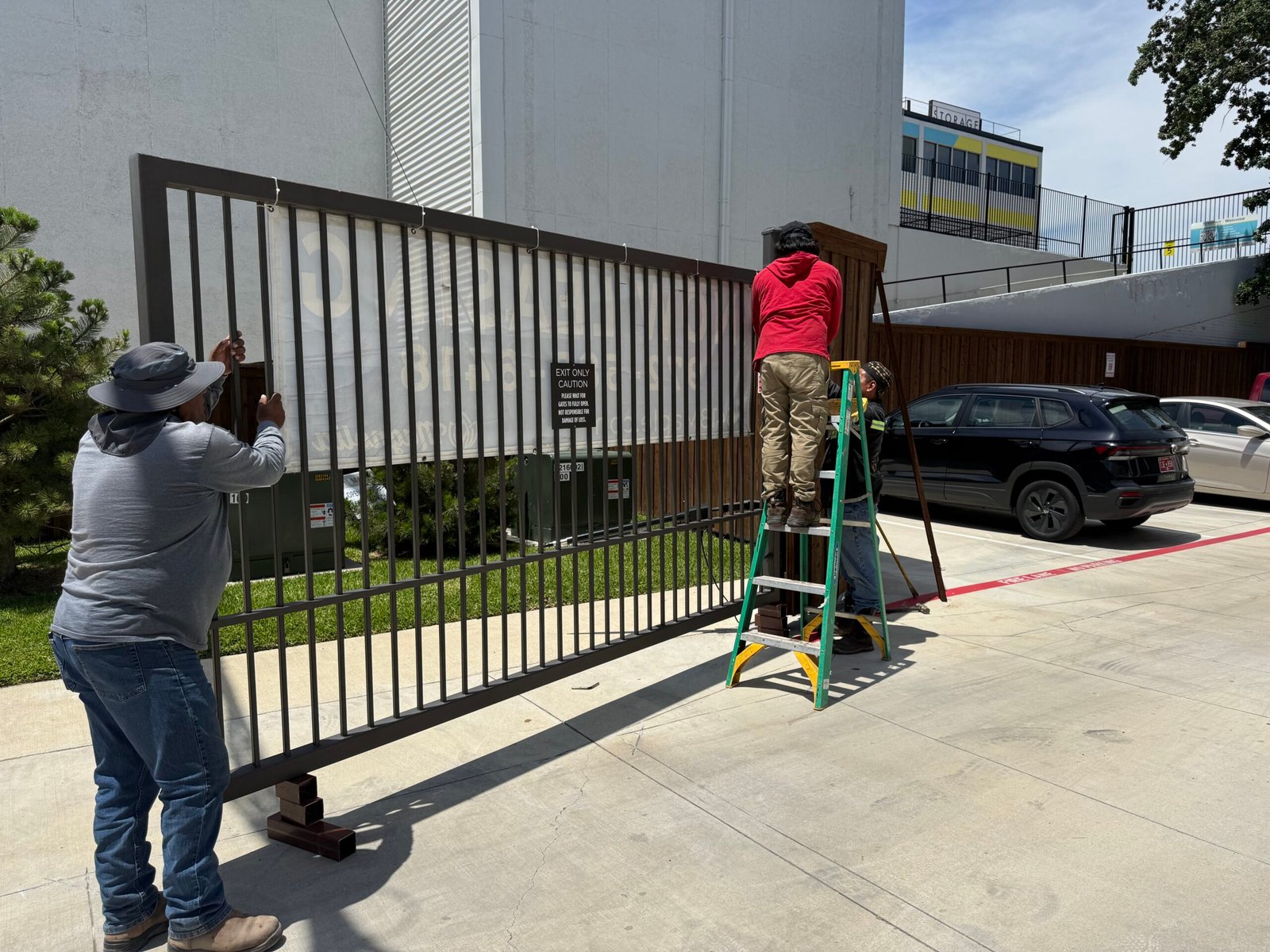 Technicians rehanging a commercial swing gate after replacing the hinges